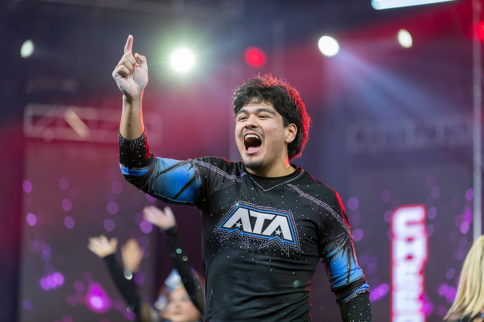 A cheer athlete celebrating on stage with one finger raised